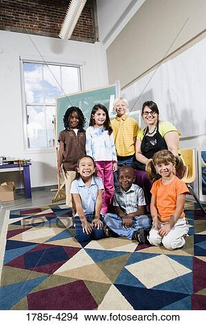Picture - Portrait of an art teacher posing with her students. Fotosearch