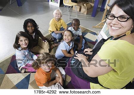 Stock Image - Portrait of an art teacher posing with her students. Fotosearch