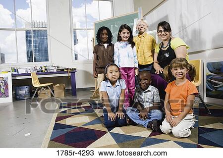 Stock Image - Portrait of an art teacher posing with her students. Fotosearch