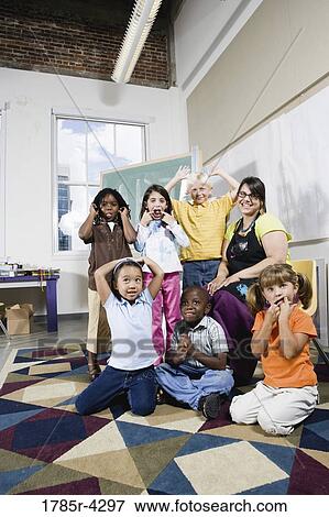 Stock Photo - Portrait of an art teacher posing with her students making funny faces. Fotosearch
