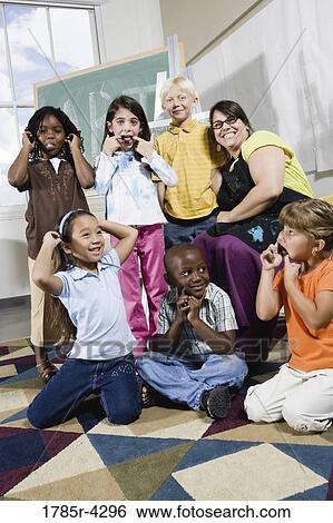 Stock Photograph - Portrait of an art teacher posing with her students making funny faces. Fotosearch