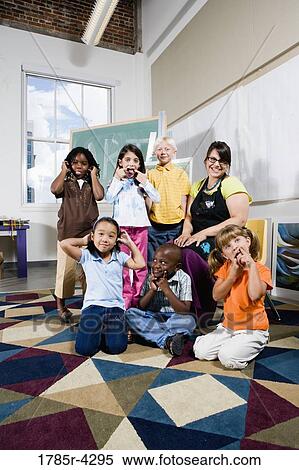 Stock Photography - Portrait of an art teacher posing with her students making funny faces. Fotosearch