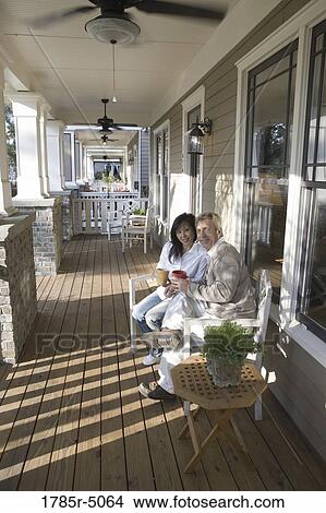 Picture - Portrait of an inter-racial couple sitting on the front porch. Fotosearch