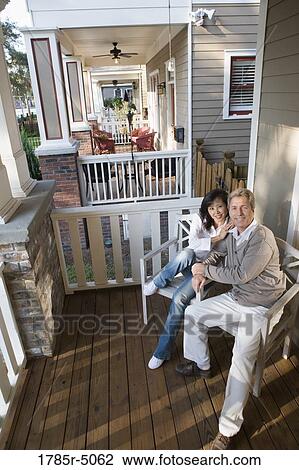 Stock Image - Portrait of an inter-racial couple sitting on the front porch. Fotosearch