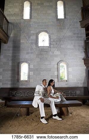 Portrait of bride and groom in white sitting on a bench inside a medieval castle View Large Photo Image Stock Image - Portrait of bride and groom in white sitting on a bench inside a medieval castle. Fotosearch
