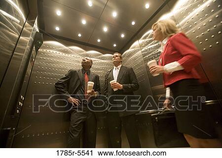 Stock Image - Portrait of business people riding in an elevator. Fotosearch