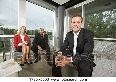 Stock Image - Portrait of business people sitting in an office lobby. Fotosearch