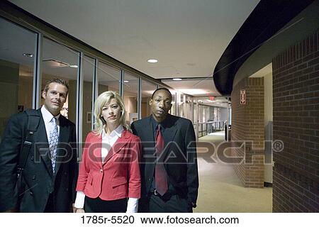 Stock Image - Portrait of business people standing in office hallway. Fotosearch