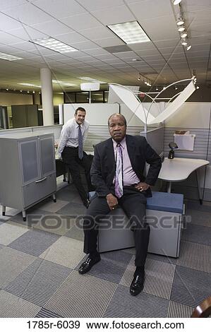 Stock Photo - Portrait of businessmen at office cubicles. Fotosearch