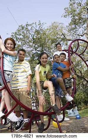 Stock Image - Portrait of children climbing on monkey bars at a playground. Fotosearch