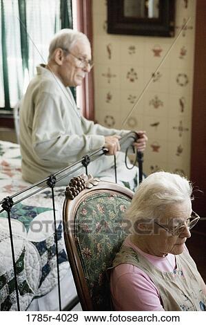 Stock Photo - Portrait of feeble senior couple sitting in bedroom. Fotosearch