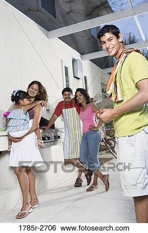 Stock Photograph - Portrait of Indian family on a patio by an outdoor kitchen. Fotosearch