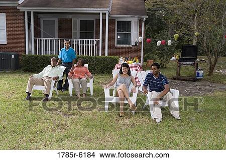 Picture - Portrait of interracial couple and family relaxing in backyard. Fotosearch