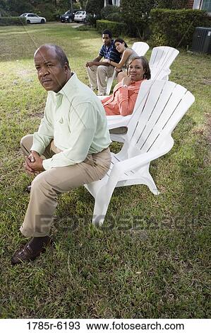 Stock Image - Portrait of interracial couple and parents relaxing in backyard. Fotosearch