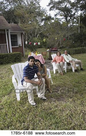 Stock Photo - Portrait of interracial couple and parents relaxing in backyard. Fotosearch