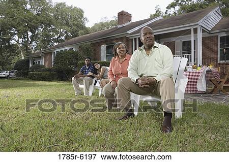 Stock Photo - Portrait of interracial couple and parents relaxing in backyard. Fotosearch