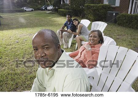 Stock Photography - Portrait of interracial couple and parents relaxing in backyard. Fotosearch
