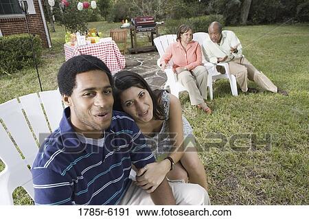 Portrait of interracial couple sitting together with parents background View Large Photo Image Stock Image - Portrait of interracial couple sitting together with parents background. Fotosearch