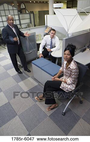 Stock Photo - Portrait of mature businessman with his two young proteges by office cubicles. Fotosearch