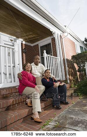 Portrait of mature couple and their son sitting on front steps of house View Large Photo Image Stock Photo - Portrait of mature couple and their son sitting on front steps of house. Fotosearch