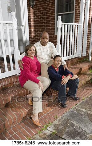 Portrait of mature couple and their son sitting on front steps of house View Large Photo Image Stock Photograph - Portrait of mature couple and their son sitting on front steps of house. Fotosearch
