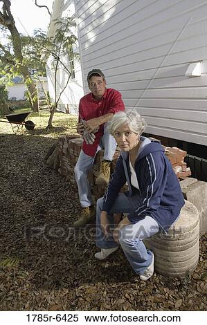Portrait of mature couple sitting on stack of bricks outside house View Large Photo Image Stock Photography - Portrait of mature couple sitting on stack of bricks outside house. Fotosearch