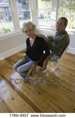 Stock Photo - Portrait of mature couple sitting inside renovated house. Fotosearch