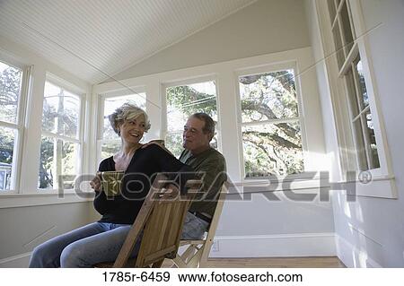 Stock Photo - Portrait of mature couple sitting inside renovated house. Fotosearch