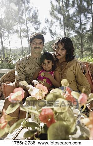 Stock Photograph - Portrait of parents sitting with their young daughter. Fotosearch