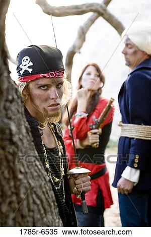 Portrait of pirates holding and threatening a captive navy officer with a sword and a gun View Large Photo Image Stock Photography - Portrait of pirates holding and threatening a captive navy officer with a sword and a gun. Fotosearch
