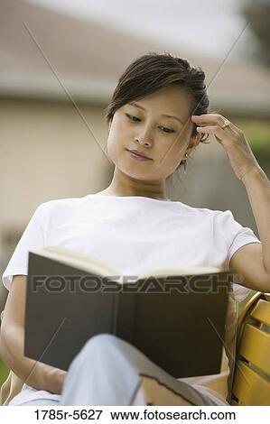Stock Photo - Portrait of pregnant woman sitting on bench reading a book. Fotosearch