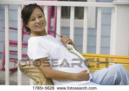 Portrait of pregnant woman sitting on bench holding a book View Large Photo Image Stock Photo - Portrait of pregnant woman sitting on bench holding a book. Fotosearch