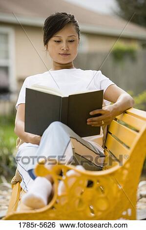 Stock Photograph - Portrait of pregnant woman sitting on bench reading a book. Fotosearch