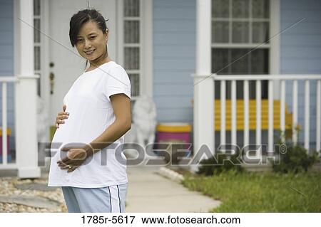 Portrait of pregnant woman standing in front of house View Large Photo Image Stock Photo - Portrait of pregnant woman standing in front of house. Fotosearch