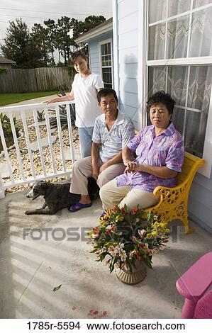 Picture - Portrait of pregnant woman with her parents seated in front porch of house. Fotosearch