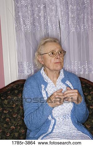 Portrait of senior woman sitting on sofa in living room View Large Photo Image Picture - Portrait of senior woman sitting on sofa in living room. Fotosearch