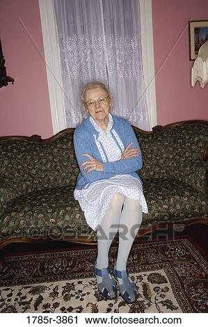 Portrait of senior woman sitting on sofa in living room View Large Photo Image Stock Image - Portrait of senior woman sitting on sofa in living room. Fotosearch