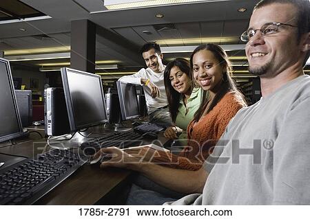 Portrait of smiling young students using computers in the library View Large Photo Image Stock Image - Portrait of smiling young students using computers in the library. Fotosearch