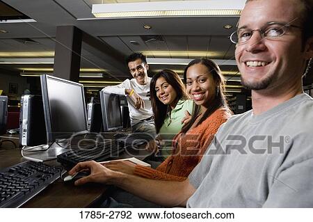 Portrait of smiling young students using computers in the library View Large Photo Image Stock Image - Portrait of smiling young students using computers in the library. Fotosearch