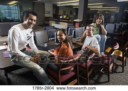 Portrait of students sitting together while using computers in the library View Large Photo Image Picture - Portrait of students sitting together while using computers in the library. Fotosearch