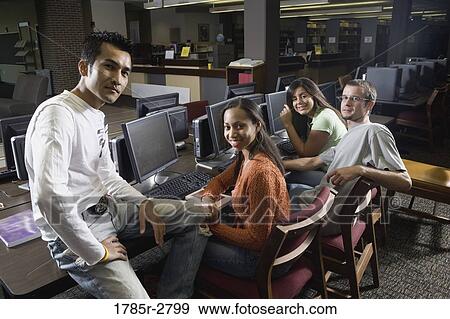 Portrait of students sitting together while using computers in the library View Large Photo Image Stock Photo - Portrait of students sitting together while using computers in the library. Fotosearch