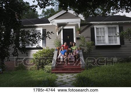 Portrait of two families sitting on the front steps of a house waving US flags View Large Photo Image Picture - Portrait of two families sitting on the front steps of a house waving US flags. Fotosearch