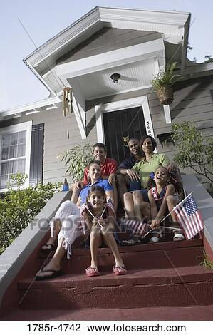 Portrait of two families sitting on the front steps of a house waving US flags View Large Photo Image Stock Image - Portrait of two families sitting on the front steps of a house waving US flags. Fotosearch