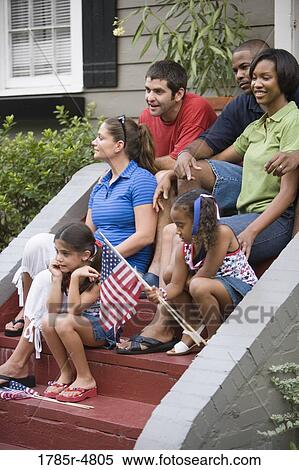 Portrait of two families sitting on the front steps of a house waving US flags View Large Photo Image Stock Photography - Portrait of two families sitting on the front steps of a house waving US flags. Fotosearch