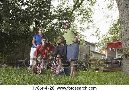 Stock Photo - Portrait of two families standing together in backyard of house. Fotosearch