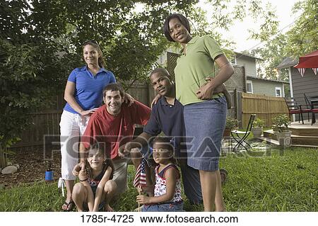 Stock Photography - Portrait of two families standing together in backyard of house. Fotosearch