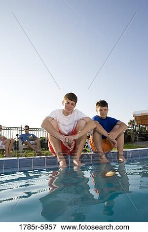 Portrait of two teenage brothers sitting beside of a swimming pool View Large Photo Image Stock Photo - Portrait of two teenage brothers sitting beside of a swimming pool. Fotosearch