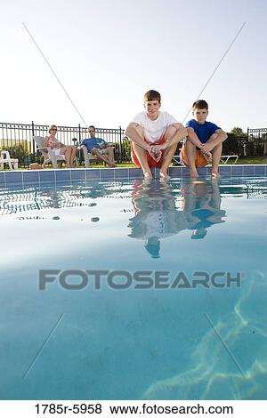Portrait of two teenage brothers sitting beside of a swimming pool View Large Photo Image Stock Photo - Portrait of two teenage brothers sitting beside of a swimming pool. Fotosearch