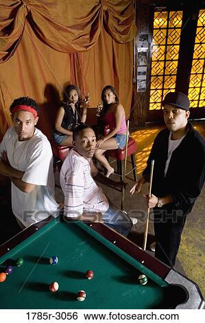 Stock Photograph - Portrait of young men in hip-hop fashion leaning against pool table. Fotosearch