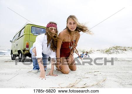 Portrait of young women in hippie fashion kneeling on sand behind van at beach View Large Photo Image Stock Image - Portrait of young women in hippie fashion kneeling on sand behind van at beach. Fotosearch